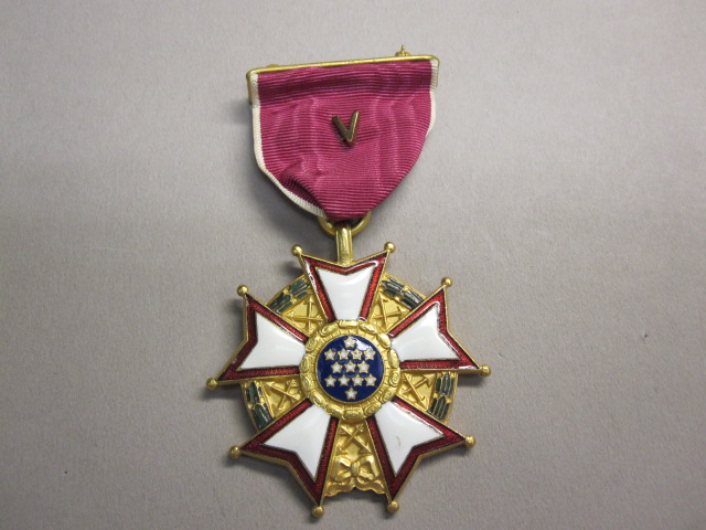 The United States Legion of Merit medal, a white-enamel five-armed cross on a crimson ribbon