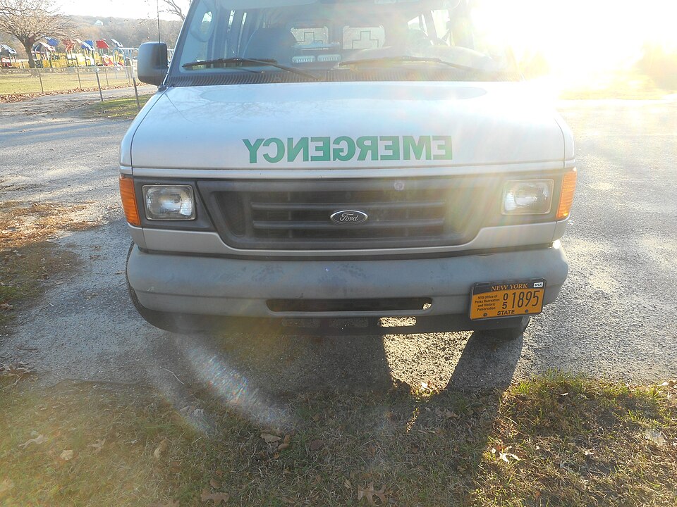 Front of an emergency van with the word EMERGENCY painted laterally inverted so it reads correctly in a mirror