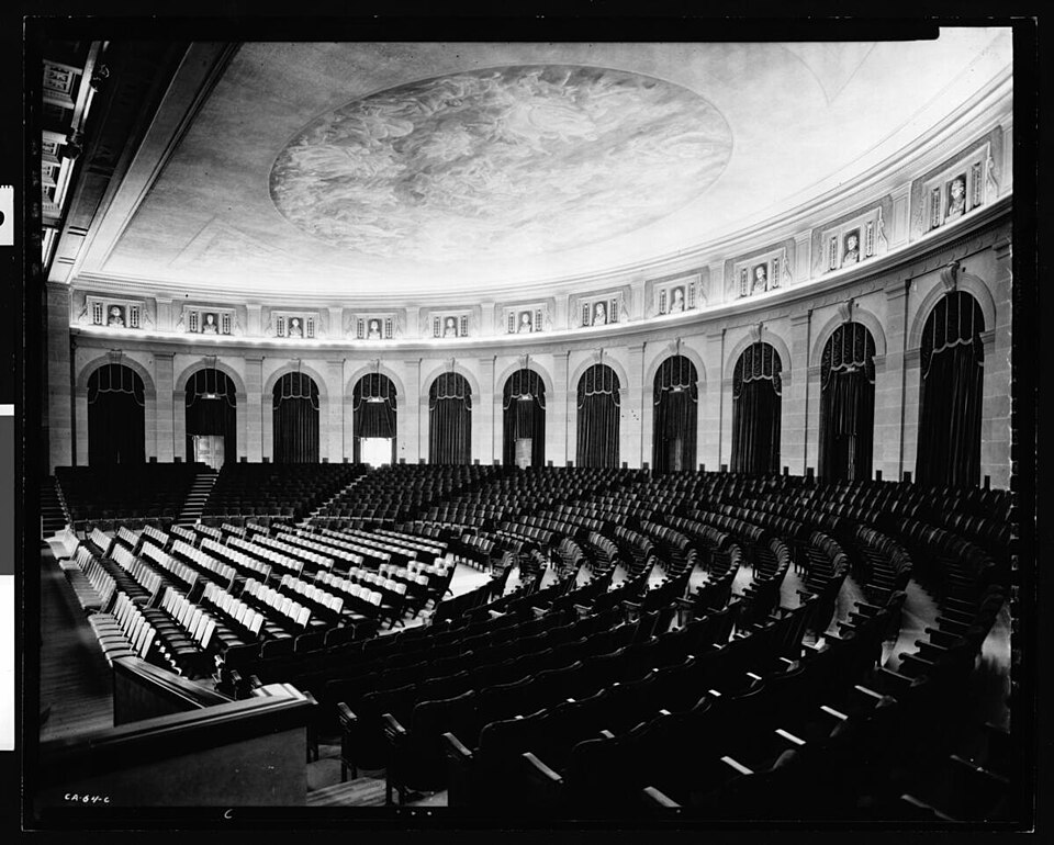 Interior of a large concert-hall auditorium with rows of seating and a domed ceiling