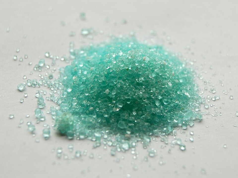 A heap of pale bluish-green ferrous sulphate heptahydrate (green vitriol) crystals.