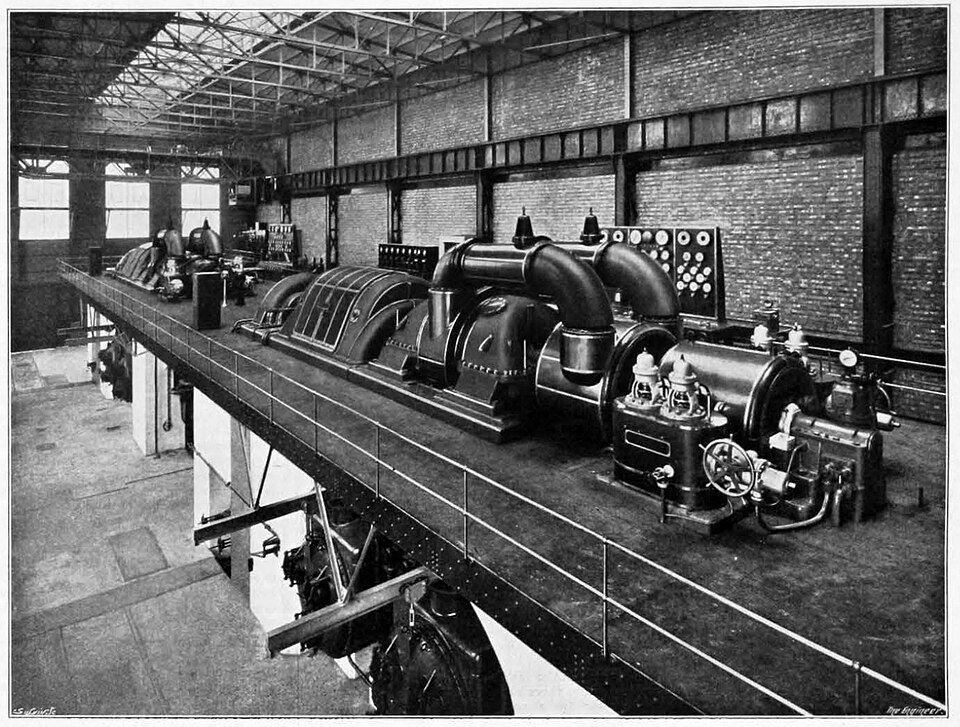 Row of large turbine-driven alternators inside a power station generating hall