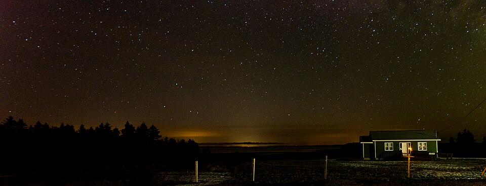Clear night sky filled with stars over a dark landscape