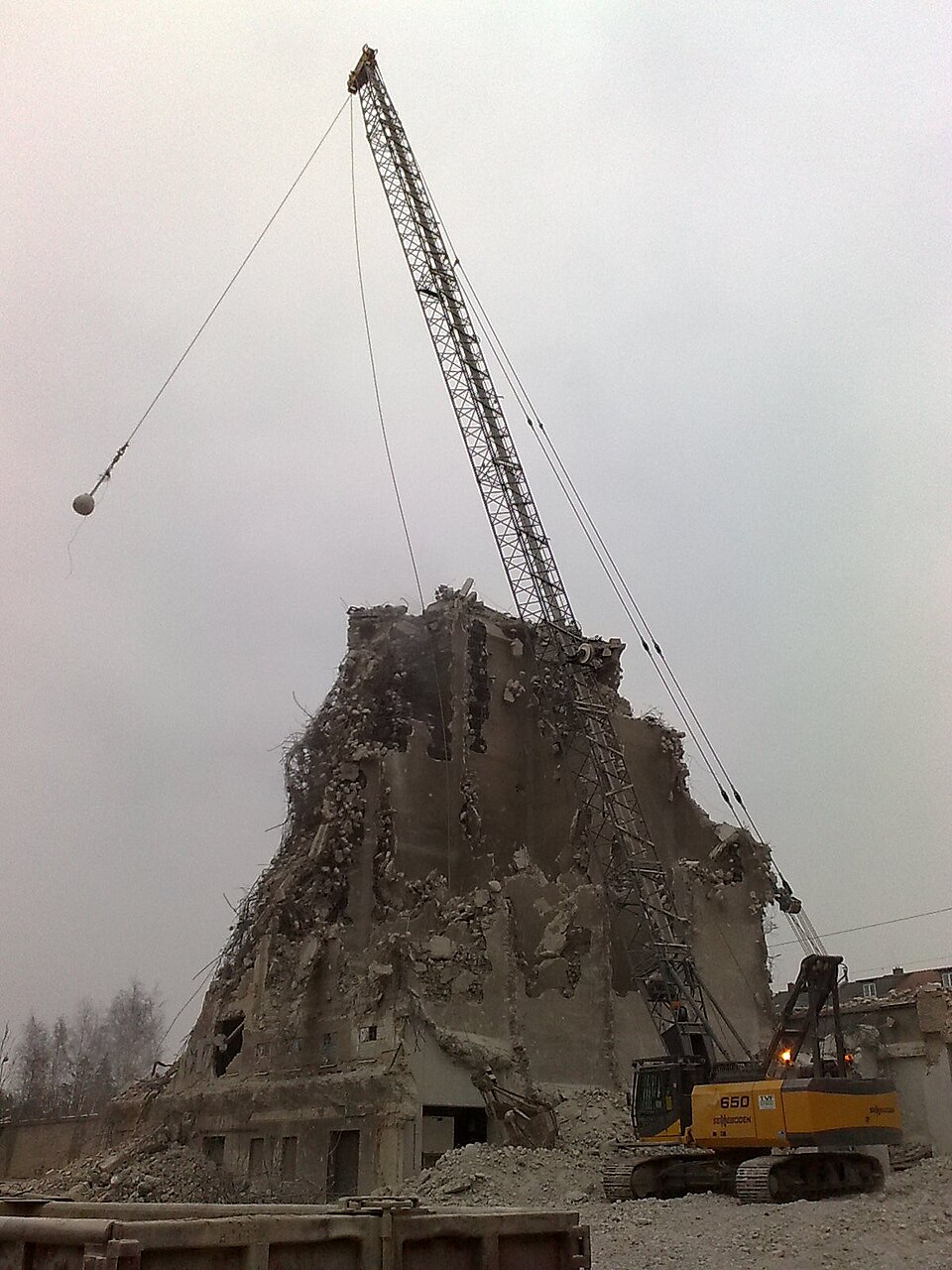 Heavy steel wrecking ball swinging from a crane at a building demolition site