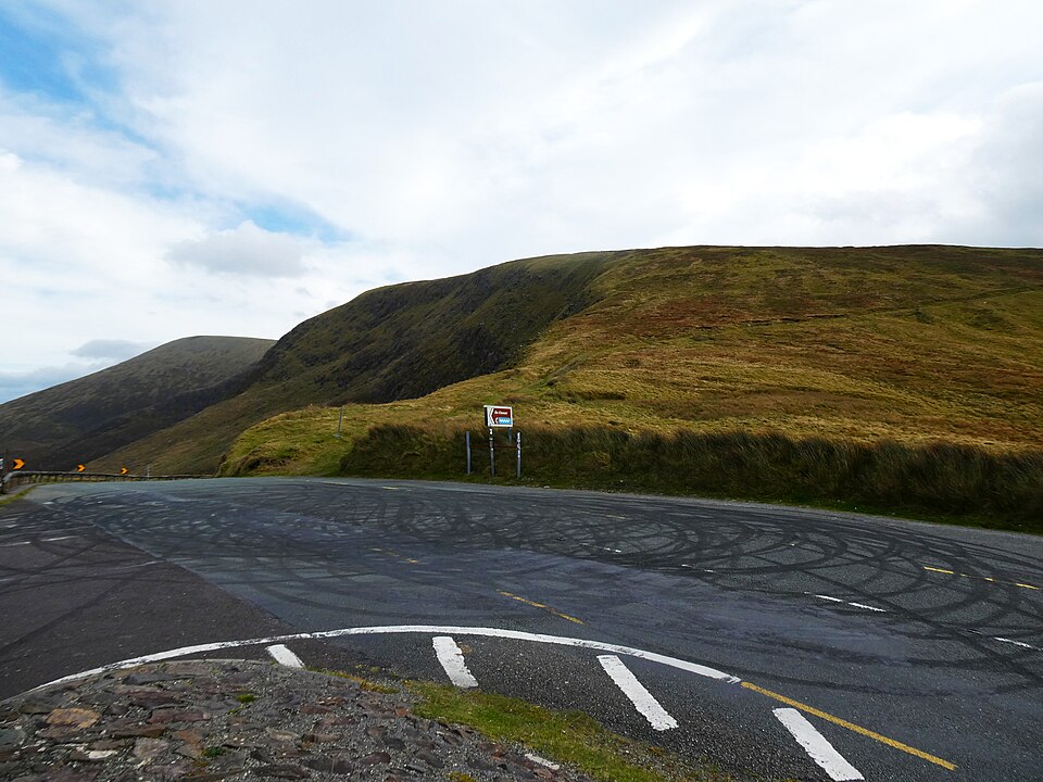 Dark tyre skid marks left by braking cars on a road surface at a bend