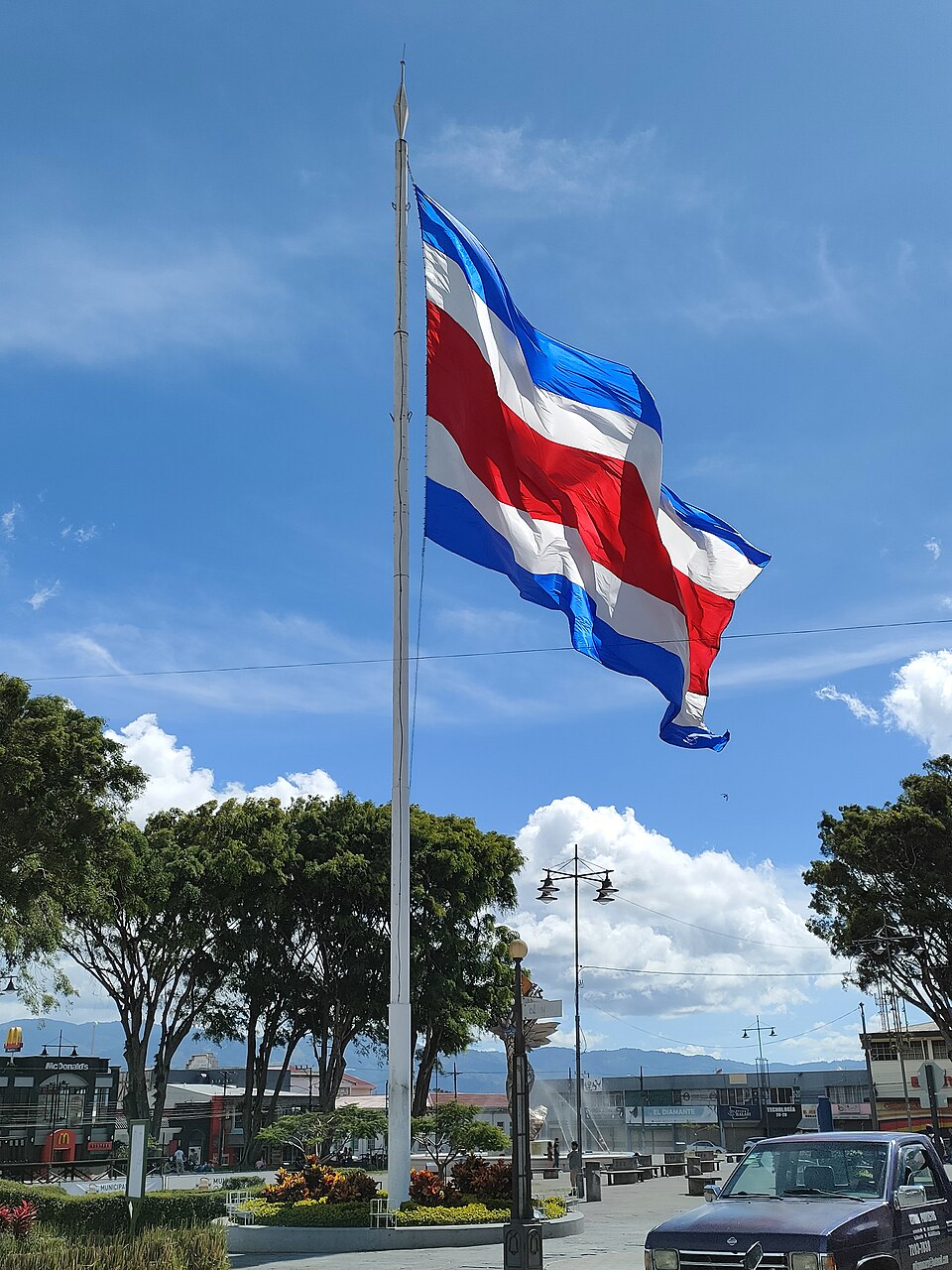 National flag of Costa Rica flying on a tall flagpole in Plaza Mayor, Cartago