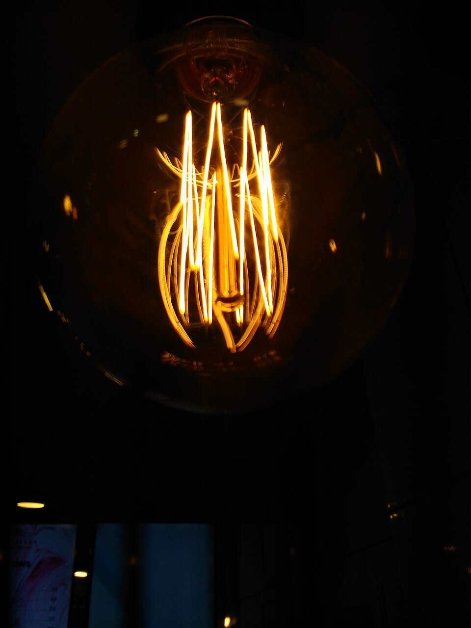 A lit incandescent bulb with its glowing filament clearly visible in the dark