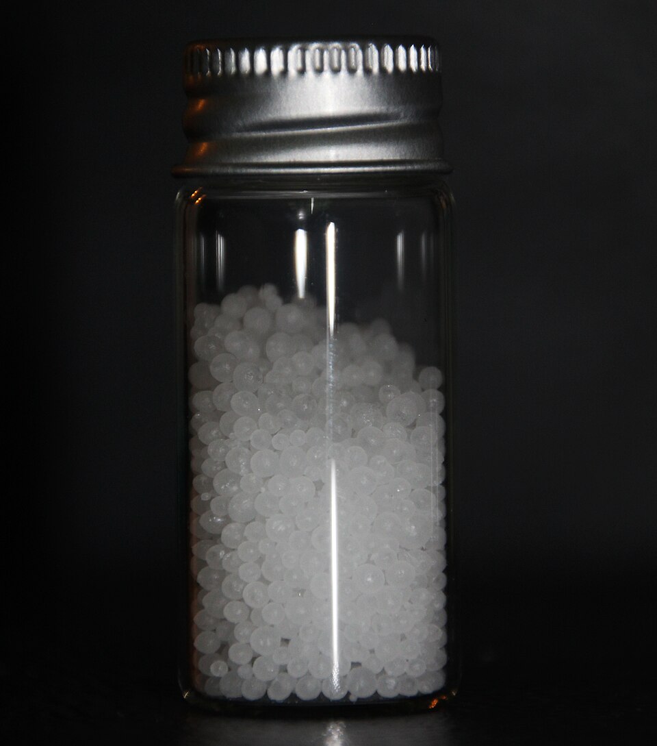 White spherical prilled urea fertilizer granules in a glass vial