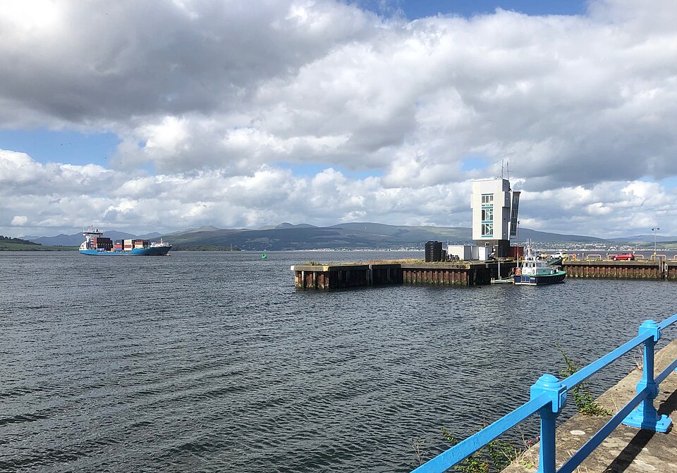 A large container cargo ship floating on the sea near a terminal