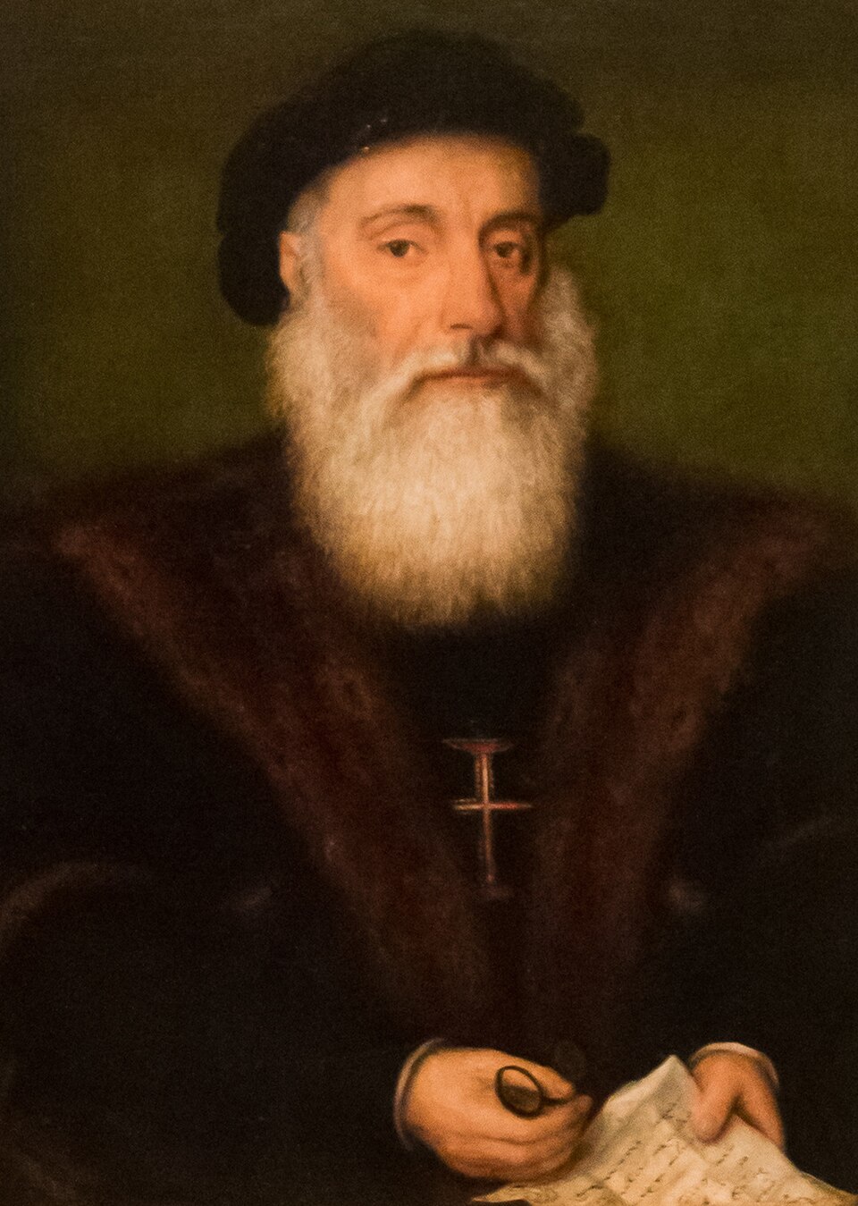 A sixteenth-century oil portrait of Vasco da Gama, a white-bearded man in a dark cap and fur-collared robe wearing the red Cross of the Order of Christ, holding a document.