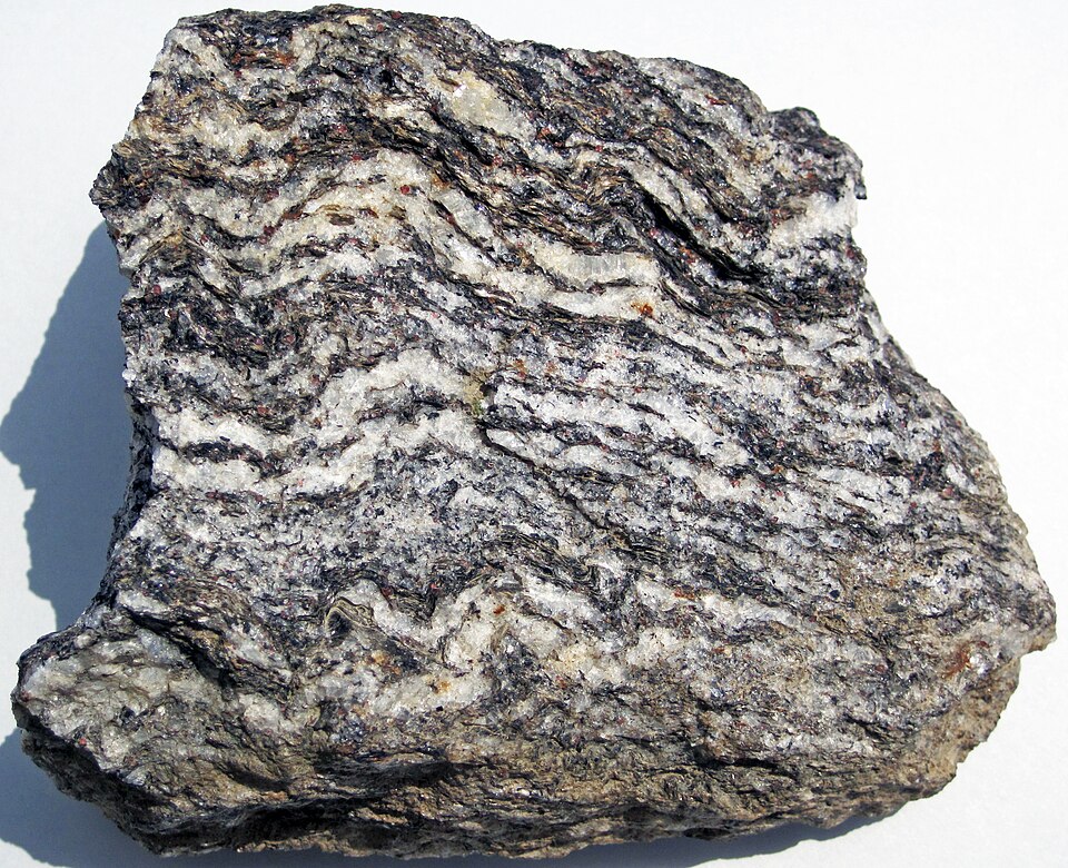 Hand specimen of gneiss from Joshimath in the Indian Himalayas, showing wavy alternating bands of white quartz-feldspar and dark mica.