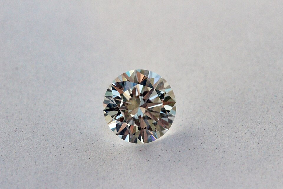 A faceted round brilliant-cut colourless diamond viewed from above, showing its many facets