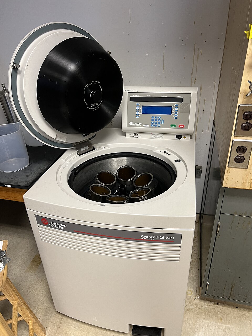 A laboratory centrifuge with its lid open, showing sample containers seated in the rotor