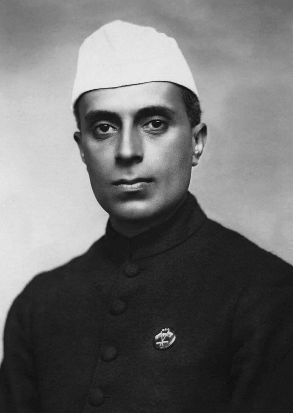 Black-and-white studio portrait of Jawaharlal Nehru wearing a white Gandhi cap and dark achkan
