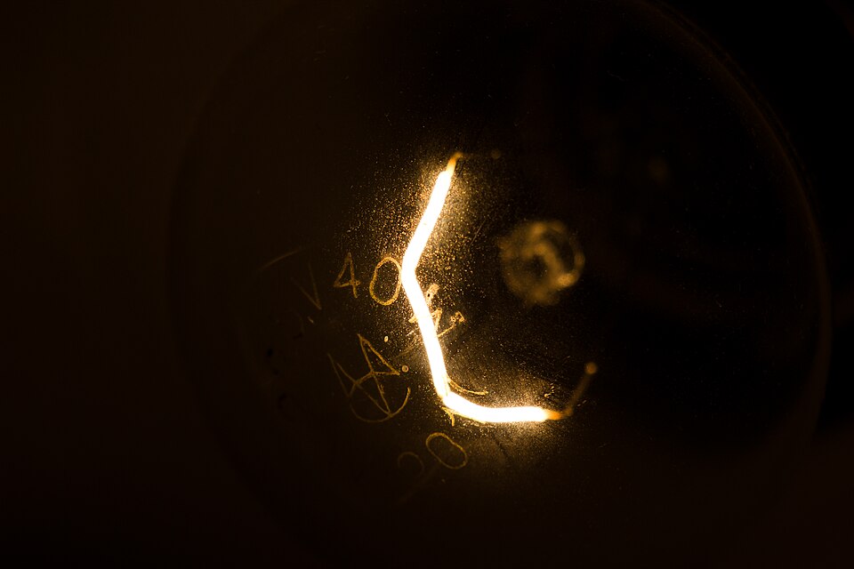 Close-up of the glowing tungsten filament inside an incandescent light bulb