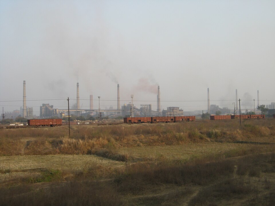 The Bokaro integrated steel plant with rows of tall chimneys and railway wagons in the foreground