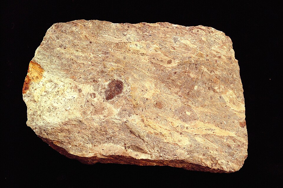 A hand specimen of volcanic tuff showing consolidated, light-coloured volcanic ash
