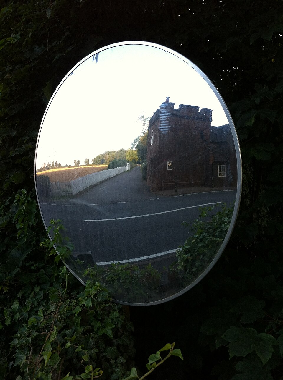 A round convex road-safety mirror giving a wide-angle upright view of a road junction