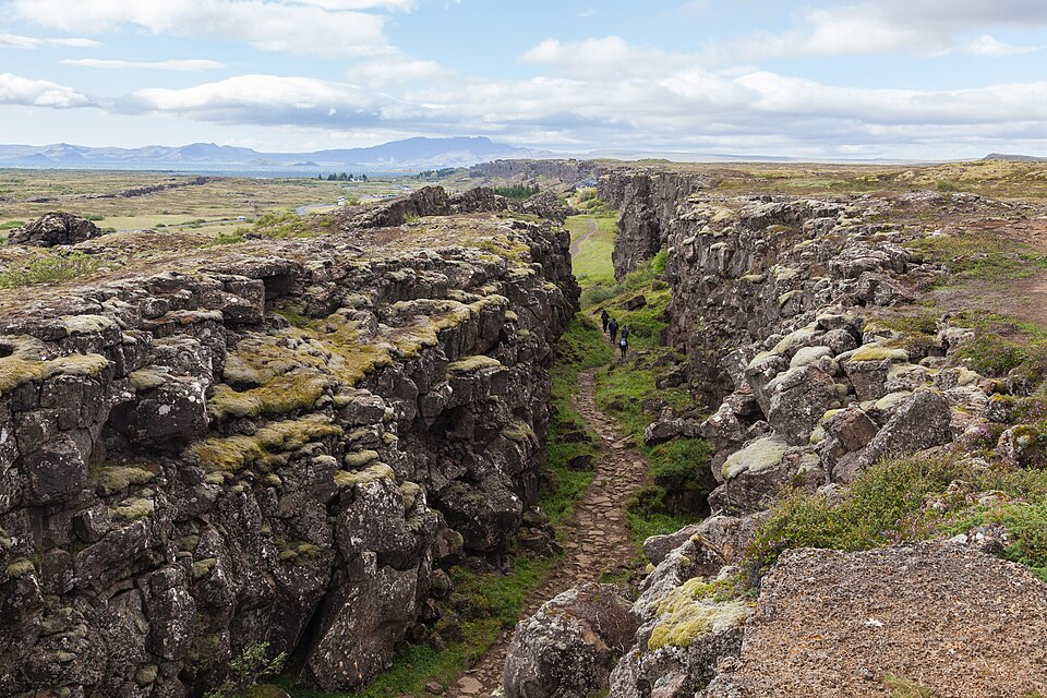 A steep rock-walled rift gorge with cliffs facing each other across a path between them