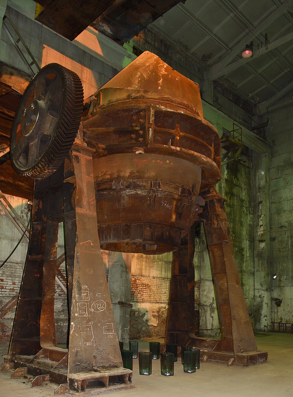 A large pear-shaped Bessemer converter vessel mounted on trunnions in a steelworks, used to mass-produce steel