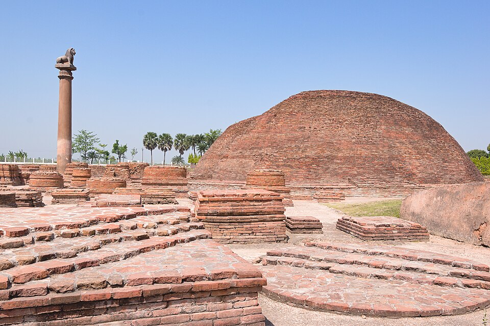 The brick Ananda Stupa dome at Vaishali, Bihar, with the Ashokan lion pillar beside it