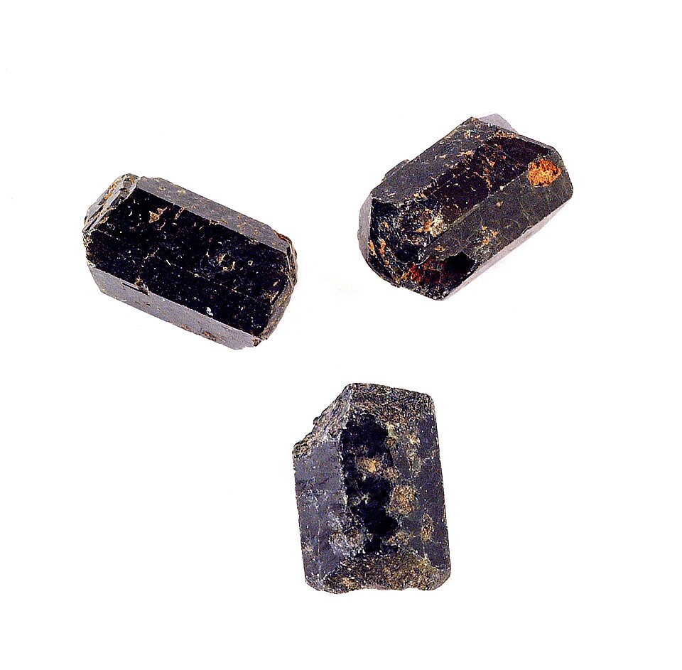 Three dark, stubby augite (pyroxene) mineral crystals on a white background
