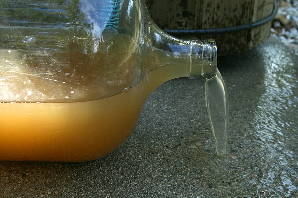 Cloudy brown water with suspended sediment in a clear glass bottle, a heterogeneous mixture