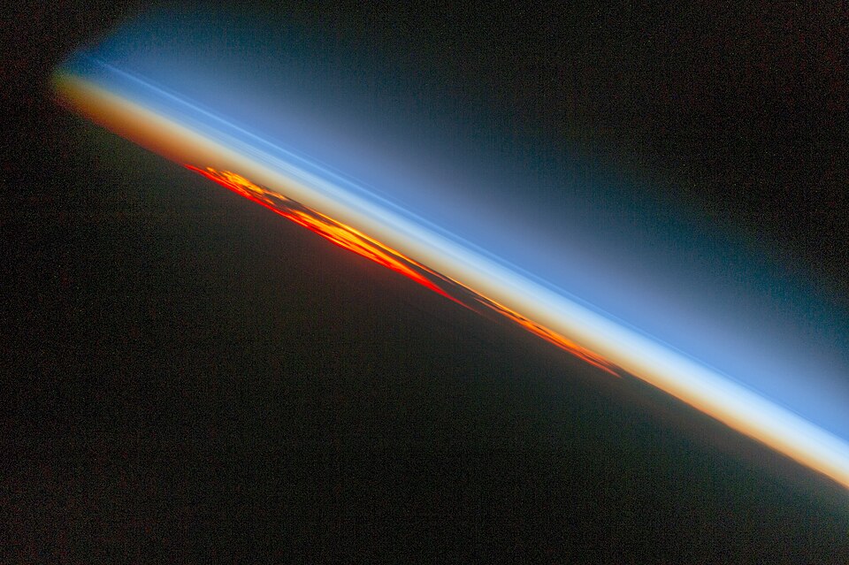 Limb view of Earth's atmosphere from the ISS showing glowing layers above the horizon