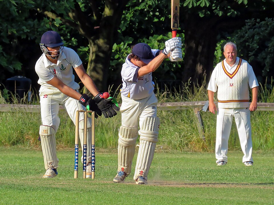A wicketkeeper taking the ball behind the stumps in a cricket match