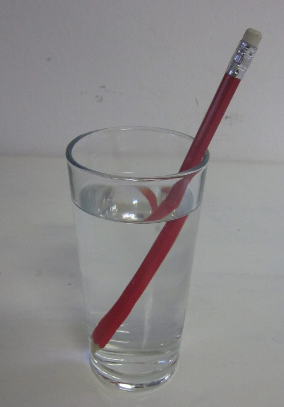 A pencil in a glass of water appearing bent at the water surface