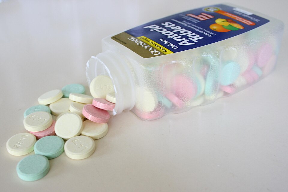 Chewable antacid tablets spilling from a bottle