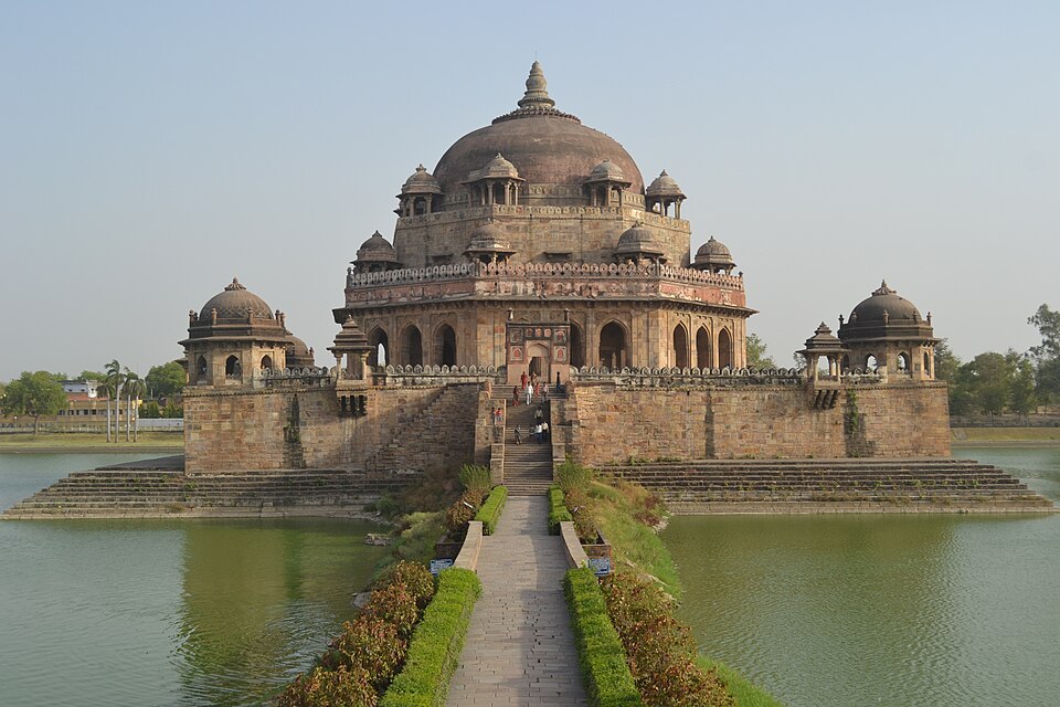 The octagonal domed sandstone mausoleum of Sher Shah Suri at Sasaram, standing on a stepped stone plinth in the middle of a large square tank, reached by a straight hedged causeway