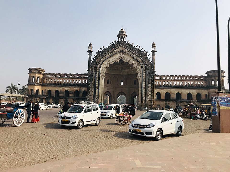 The Rumi Darwaza in Lucknow, an ornate Awadhi gateway with a large central pointed arch and decorated facade, seen in daylight above a busy street
