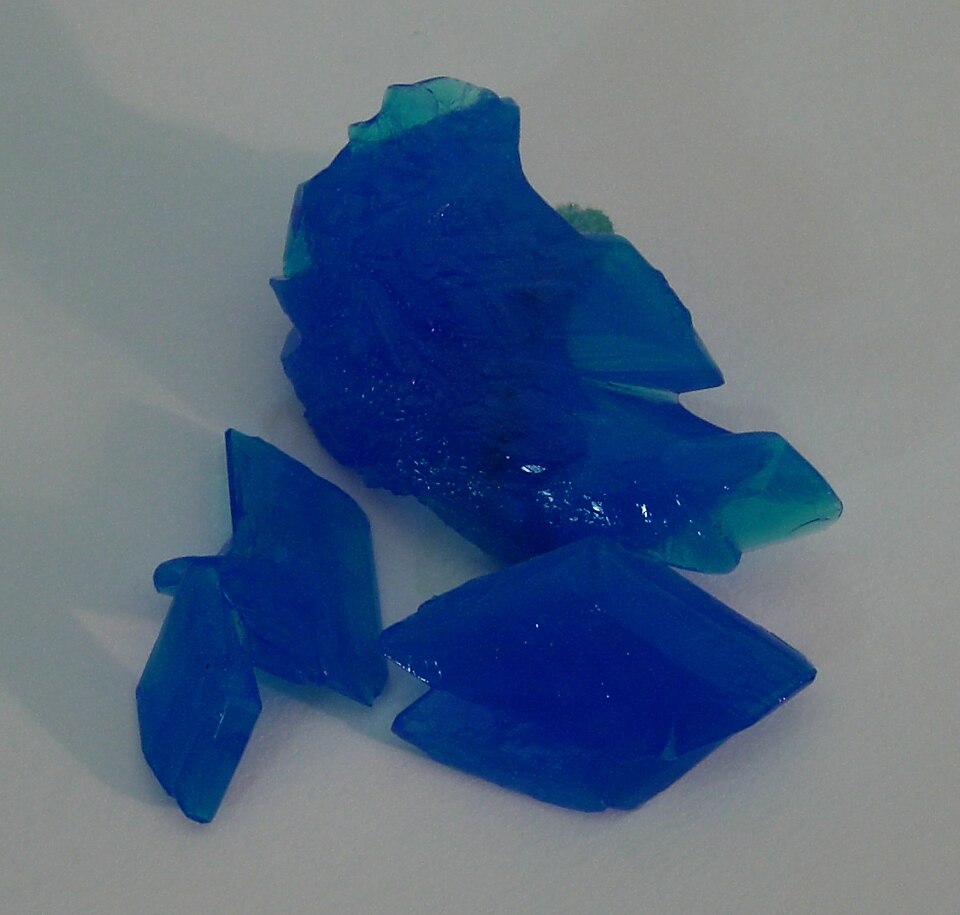 Bright blue crystals of copper sulphate pentahydrate (blue vitriol) on a white surface