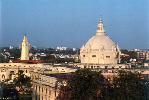 The large white dome of the Vidhan Bhawan (Uttar Pradesh Legislative Assembly building) and a clock tower rising above the Lucknow skyline in daylight