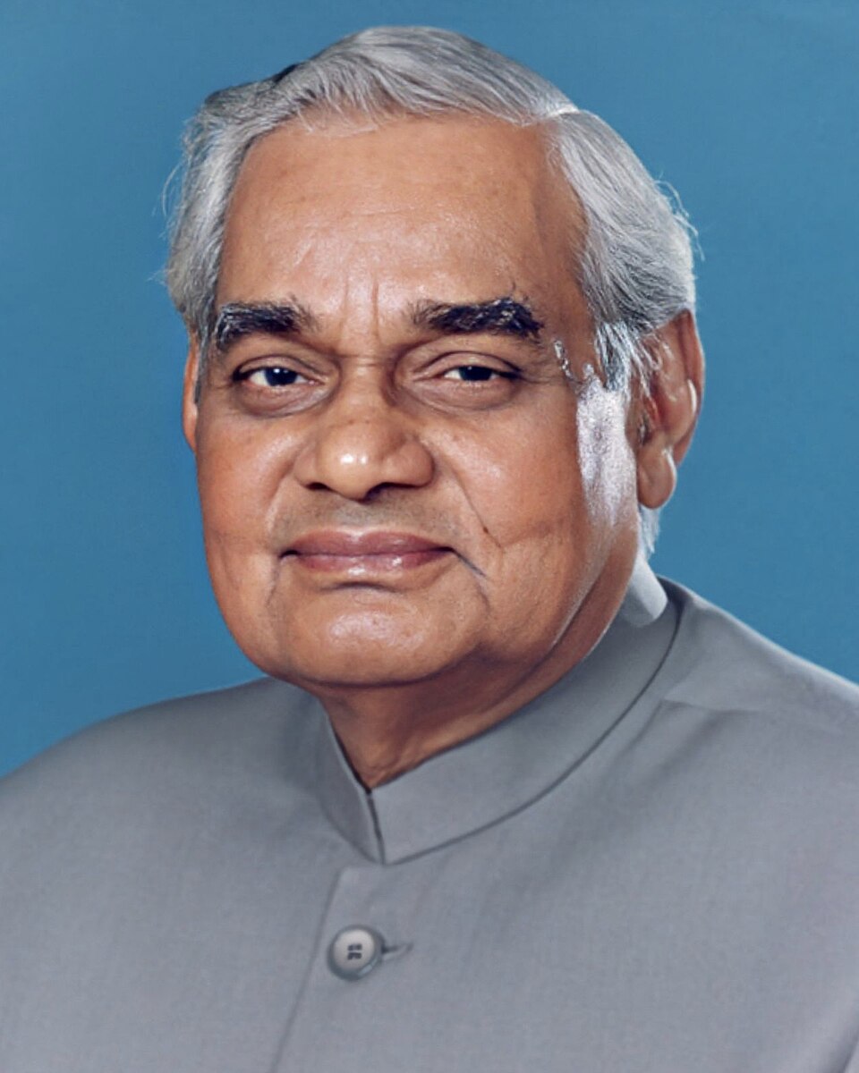 Official portrait of an elderly man with grey hair wearing a grey bandhgala jacket against a blue background