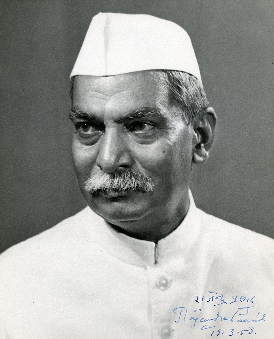 Black-and-white portrait of an elderly moustachioed man wearing a white Gandhi cap and white tunic, signed Rajendra Prasad and dated 1958