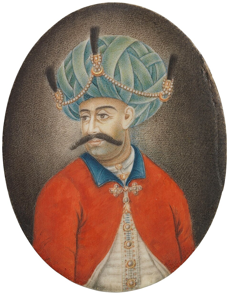 Oval miniature painting of a moustachioed man wearing a large green plumed turban with pearl ornaments and a red coat over an embroidered tunic
