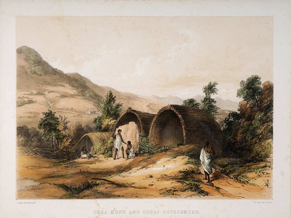 Two half-barrel-vaulted Toda huts (munds) with low arched doorways set among the grassy Nilgiri hills