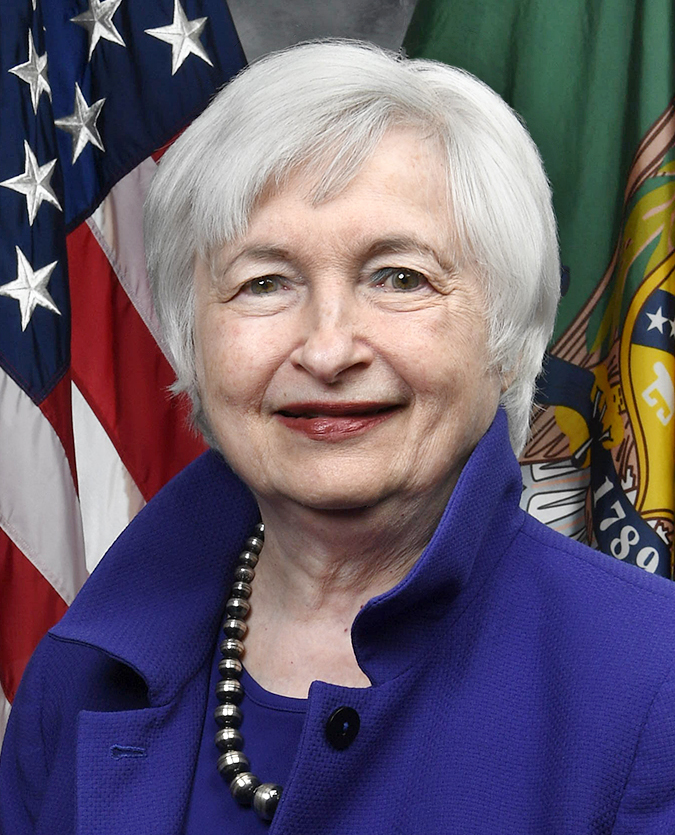 Official portrait of Janet Yellen, a woman with short white hair in a purple jacket, smiling in front of the US flag and a Treasury Department flag.