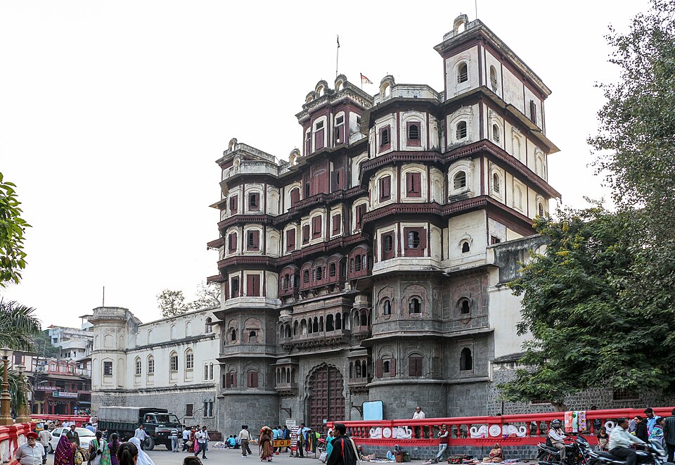 The tall multi-storeyed wooden and stone facade of the Rajwada palace in Indore, with tiered balconies rising above the street