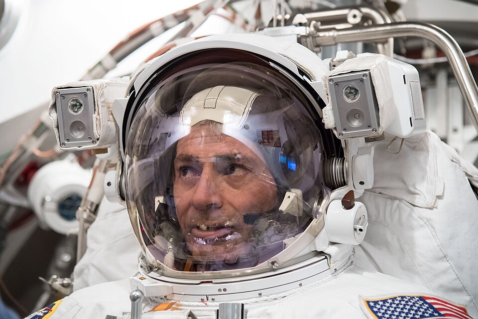 Close-up of NASA astronaut Mark Vande Hei inside the helmet of a white spacesuit during spacewalk training