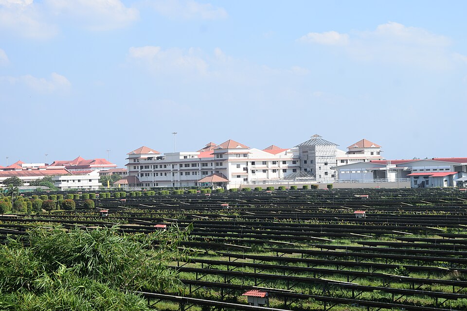 Rows of ground-mounted solar panels covering the field in front of the terminal buildings at Cochin International Airport