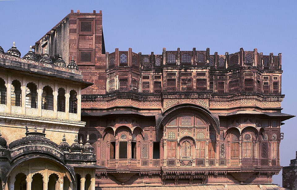 Carved red sandstone palace facade inside Mehrangarh Fort at Jodhpur, tiers of latticed jharokha windows above arched balconies