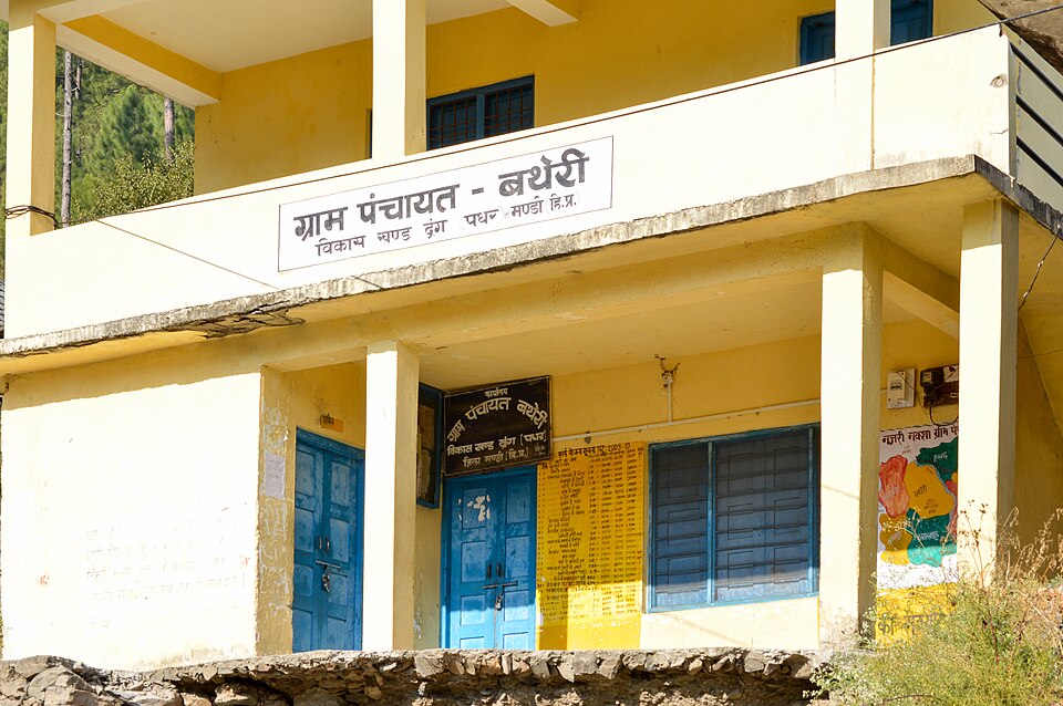 A yellow two-storey village panchayat building with a Devanagari signboard reading Gram Panchayat Batheri and painted notice boards along the veranda