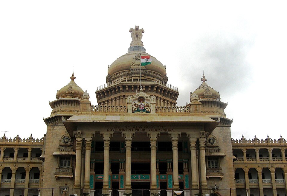 The granite facade and central dome of Vidhana Soudha in Bengaluru, its portico carrying the inscription Government Work Is God's Work