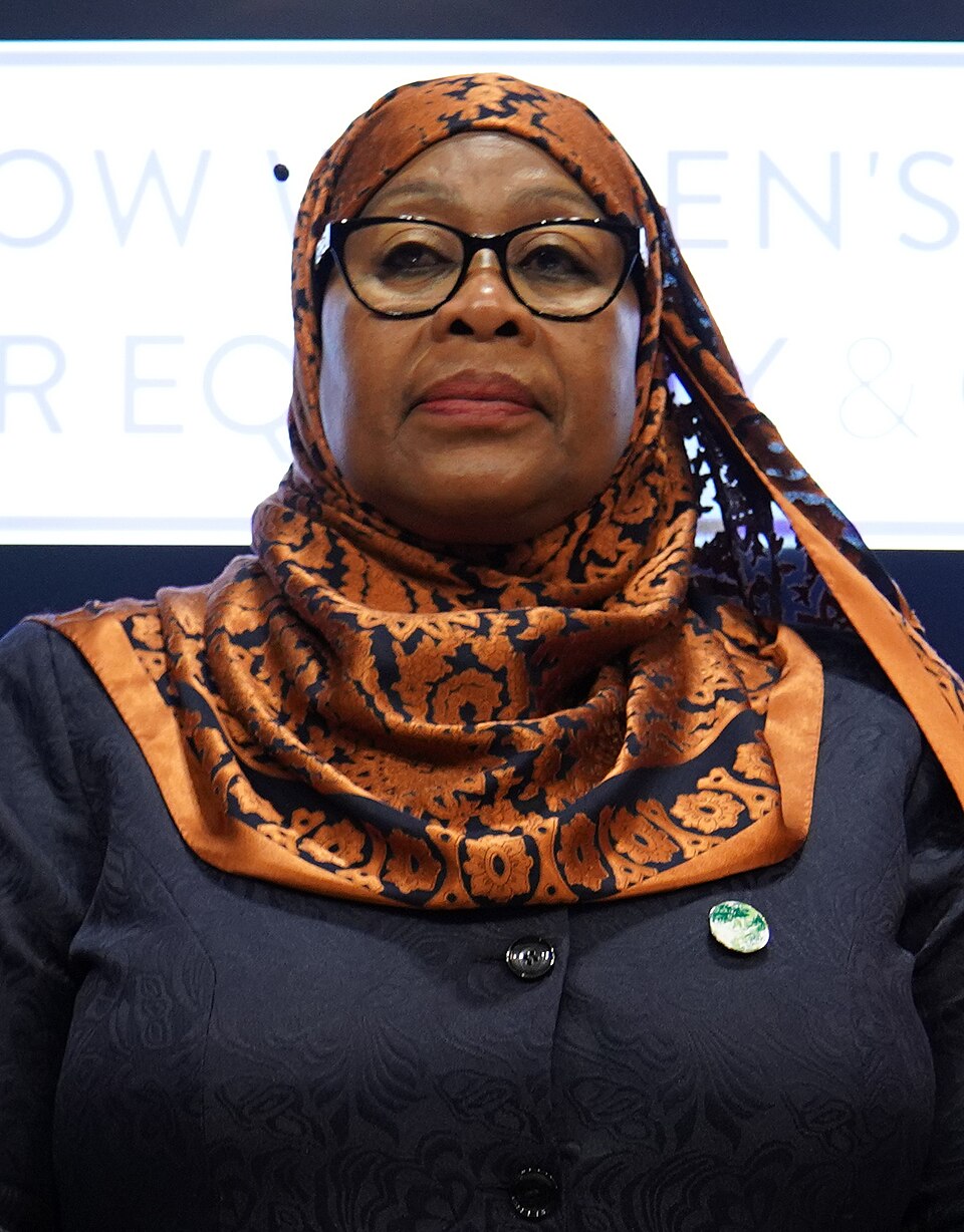 Portrait of Samia Suluhu Hassan in a patterned orange and black headscarf and dark jacket at a conference