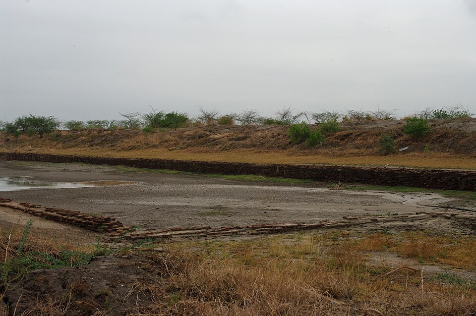 The large rectangular basin at Lothal, its sides lined with courses of baked brick, excavated and dry under a grey sky