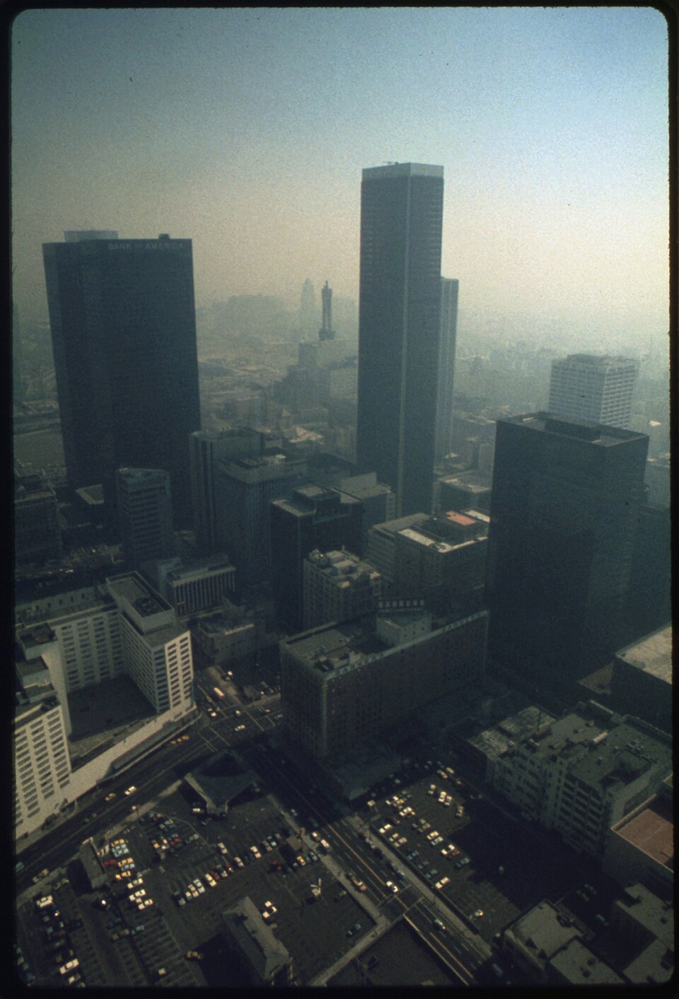 Downtown Los Angeles towers seen from above, their outlines fading into a thick brown-grey haze that blots out the horizon