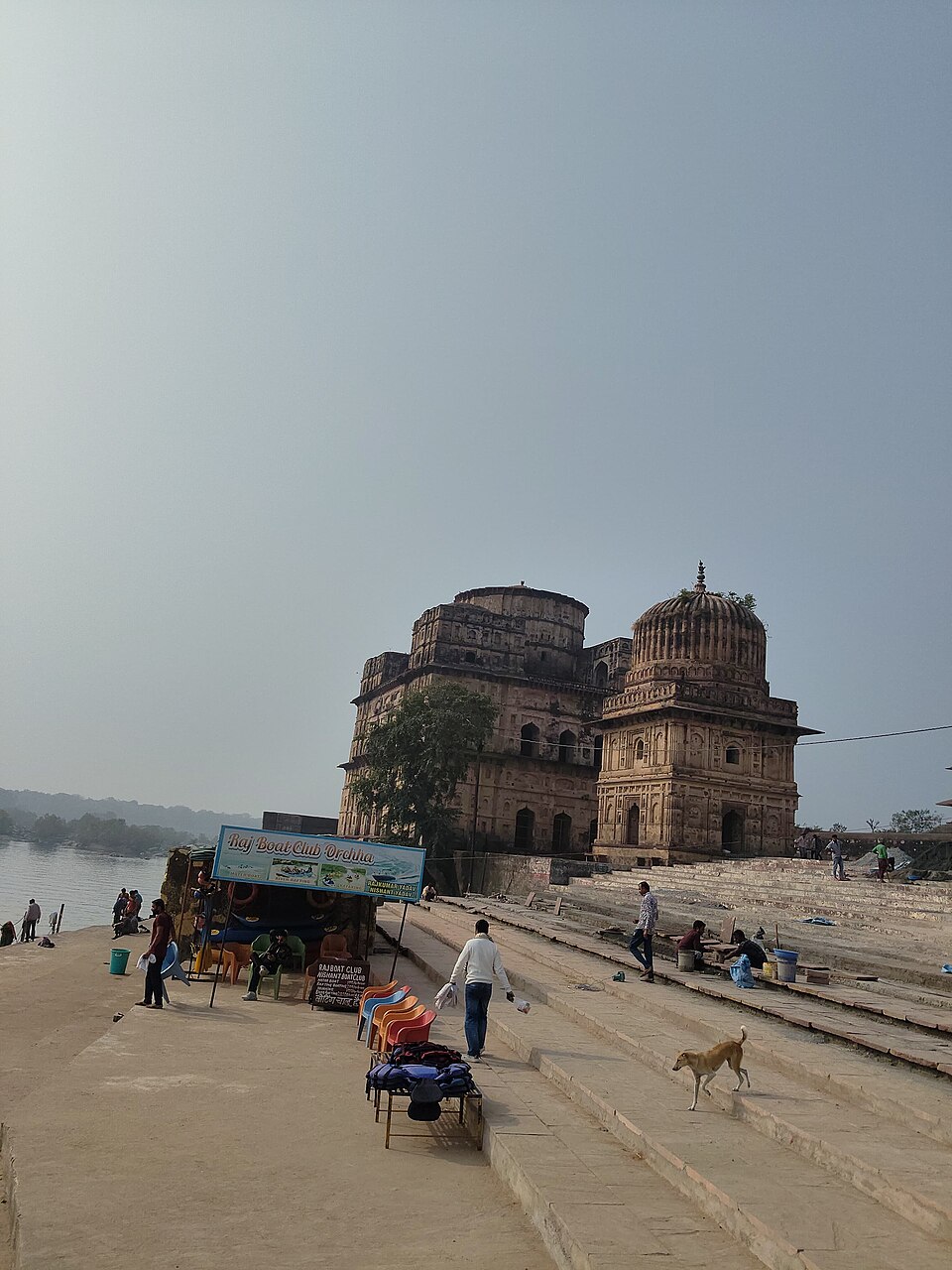 The domed Bundela cenotaphs (chhatris) of Orchha standing on the ghats beside the Betwa River, with riverside steps in the foreground