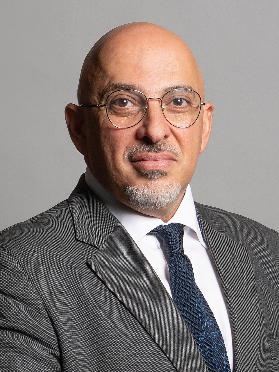 Official studio portrait of Nadhim Zahawi, a bald bespectacled man with a grey goatee wearing a grey suit and dark blue tie